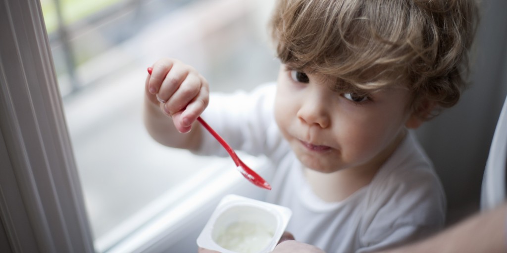 Toddler boy eating yogurt, portrait